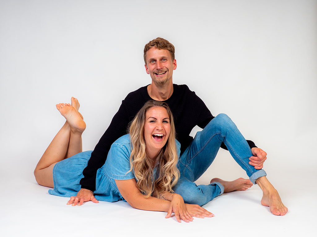 man sitting on floor with woman lying under his arm laughing taken by family photographer in Braintree